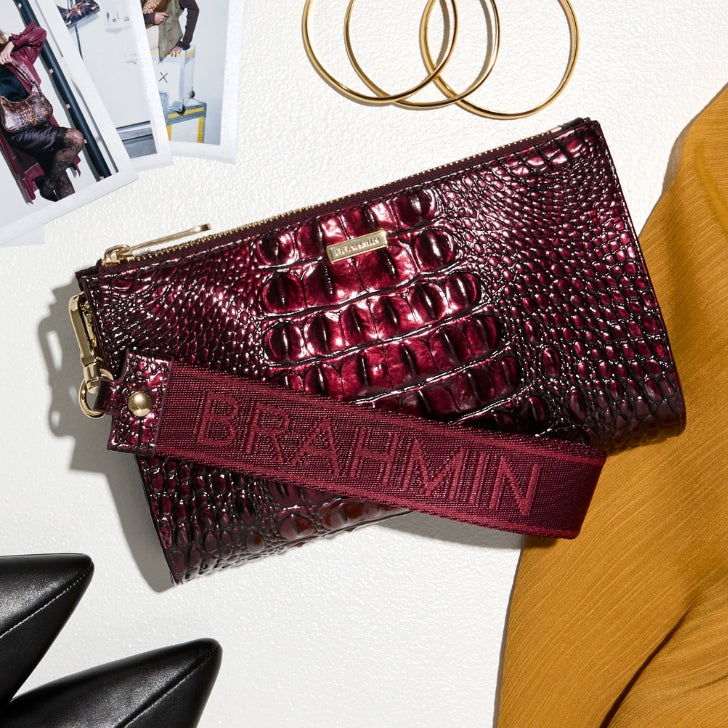 Brahmin burgundy wristlet with glossy embossed texture, zip top closure, gold tone hardware and wide logo strap