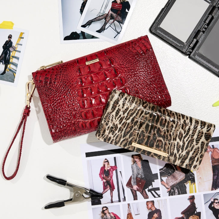 Brahmin red crocodile-embossed leather wristlet, leopard-print wallet, and tan crocodile-embossed wallet with gold hardware styled over fashion lookbook photos on a white creative workspace.